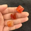 Detailansicht von drei quadratisch geschnittenen roten Karneol-Achat-Cabochons mit Textur. - Roter Achat
