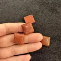 Nahaufnahme von funkelnden quadratischen Goldstein-Cabochons für DIY-Schmuckzubehör-Komponenten - Gold-Sandstein