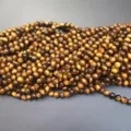 Macro detail of natural tiger eye stone beads with golden brown chatoyancy texture - 2mm (Approx. 180 Pieces/Pack) / Grade A+ Tiger's Eye