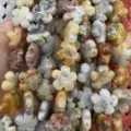 Macro detail of various natural stone beads shaped like five-petal plum blossoms for DIY - 25 Pieces/Strand (15x15x5mm) / Crazy Agate