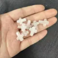 Close-up detail of small white cross-shaped natural stone beads held in a person's palm - Approx 12*16mm / 1 Bead / Rose Quartz