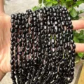 Hand holding polished irregular black natural stone beads for DIY jewelry making 4-6mm - Obsidian