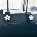 Detailed view of black car seat headrest hooks with cute white flower design for interior. - Style 10