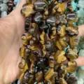 Macro view of natural tiger eye stone beads carved in plum blossom shapes for DIY jewelry - 25 Pieces/Strand (15x15x5mm) / Tiger Eye