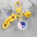 Yellow metal keychain with cute glass ball pendant, blue stones and pink dry flower decor. - Style 1