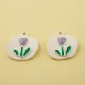 Close up view of white alloy tulip charms with purple enamel and green leaves for DIY jewelry making. - Purple Round Badge