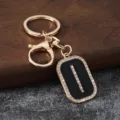 Gold metal rhinestone letter keychain detail, black enamel pendant with sparkling crystals. - Letter I