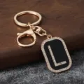 Gold metal initial L keychain with sparkling rhinestones and black enamel pendant accessory. - L