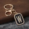 Detailed close-up of a golden metal keychain featuring a sparkling rhinestone letter W charm. - Letter W