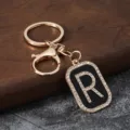 Close-up view of the sparkling rhinestone letter R pendant on a stylish gold keychain. - Letter R