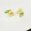 Gros plan de pendentifs muguet avec feuilles vertes et anneaux dorés pour la bijouterie. - Jaune