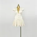 Primo piano del mini abito beige con scollo a V profondo, vita stretta e bottoni delicati. - Taglia S / Albicocca