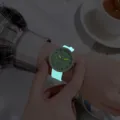 Dettaglio di orologio al quarzo luminoso con lancette e cinturino in silicone al buio. - Verde chiaro