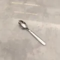 Vue détaillée de cuillère en acier inoxydable, surface polie et manche lisse pour le repas. - Petite Cuillère Pointue