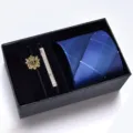 Details of the blue striped tie, golden brooch, and silver tie clip set in a black box. - KHVA8018-1B