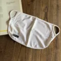 Breathable white mesh sun protection face mask detail showing hanging ear design and label. - White