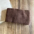 Close-up detail view of a cozy brown knit headband, wide winter warm hair accessory. - Coffee