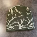 Détail en gros plan d'un bonnet en tricot vert avec un motif de camouflage de branches. - M / Vert Militaire