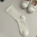 Primer plano de calcetines blancos con volantes y pequeño botón de flor, suave textura tejida. - Talla única / Blanco Crema