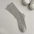 Primer plano de calcetines grises acanalados con volantes y un lindo botón de flor. - Talla única / Gris claro