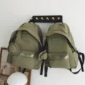 Detailansicht des grunen Rucksacks aus Segeltuch mit Fronttasche und Weblogo. - S / Armeegrün