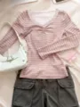 Top rosa a maniche lunghe con scollo a V e pizzo delicato abbinato a pantaloni cargo scuri. - Taglia S / Top / Strisce Rosa