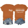 Detail view of the caramel senior mom class of 2027 short sleeve t-shirt graphic apparel. - S / Tops / Burnt Orange (White Font)