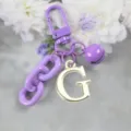 Porte-clés en alliage élégant avec lettre dorée, chaîne colorée et grelot décoratif. - Lettre G