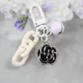 Stilvoller weißer Metall-Schlüsselanhänger mit lila Glocke und schwarzem Kamelien-Strassanhänger. - Stil 4