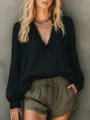 Detail shot of women's black long sleeve top featuring V-neckline with delicate ruffle details. - Black