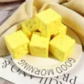 Nahaufnahme von käseförmigen PU-Squishy-Spielzeugen zum Stressabbau auf einem weißen Teller - Käsewürfel / 7x7cm / Gelb