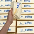 Nahaufnahme einer Hand, die ein realistisches Butter-Stab-Stressspielzeug drückt - Butterrührstab / 24cm