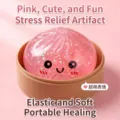 Nahaufnahme eines rosa glitzernden Brötchen-Squishys mit süßem Gesicht im Korb - Gel Gesichtsausdruck Bun Mit Dampfgarer / Rosa