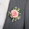 Gedetailleerde close-up van een roze kunstmatige rozen corsage op een grijs trouwpak. - Roodroze boutonnières