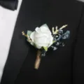 Elegante bottoniera di rose bianche con bacche blu e stelo in juta, ideale per matrimoni. - Corsage / Bianco