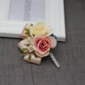 Gedetailleerd overzicht van de kunstmatige rozen boutonnière met roze en witte bloemen en lint. - Corsage / Lichtroze