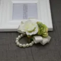 Dettaglio in primo piano del corsage da polso di rosa artificiale con bracciale di perle. - Corsage da polso / Bianco e Verde