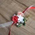 Close-up detail of artificial rose wrist flower with red and white ribbons for wedding. - Wrist Corsage / Red