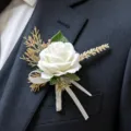 White artificial rose boutonnière with green leaves and ribbon for wedding suit accessory. - White Corsage