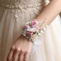Nahaufnahme eines zarten rosafarbenen Rosen-Handkorsetts mit Perlen und weißer Schleife. - Handgelenk-Korsagen (Stil C)