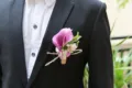Detail view of the purple calla lily boutonniere with green leaves and jute twine for weddings. - Purple