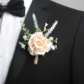 Dettaglio di boutonniere da sposa con rosa champagne elegante, foglie verdi e spago. - Corsage / Champagne
