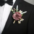 Primo piano dettagliato di un elegante fiore artificiale da giacca su un abito nero. - Corsage / Caffè