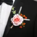 Vista dettagliata della boutonnière di rosa artificiale con foglie verdi per abito da sposo. - Corsage / Cuore Rosa