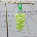 Gros plan détail du porte-clés raisin en acrylique vert suspendu sur support, accessoire. - Raisins vert herbe