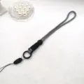 Gros plan détaillé de la lanière de téléphone tressée noir et blanc avec boucle et anneau. - Corde longue / Noir et blanc / noir