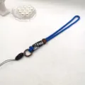 Gros plan detaille de la laniere de poignet pour telephone tisse bicolore faite a la main. - Corde longue / Bleu/Noir Blanc