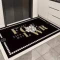 Black PVC entryway door mat with camellia flower pattern and gold typography for home decor. - FOELWR