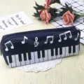 Vista detallada de un estuche cuadrado azul oscuro con estampado de teclas de piano y notas. - Negro
