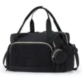 Detailed close-up view of black quilted diaper bag texture and exquisite golden hardware. - Black
